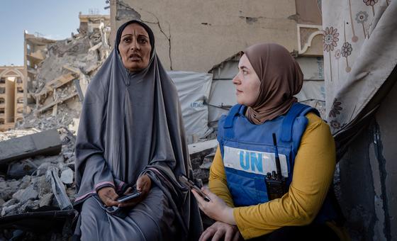 Una trabajadora del PMA habla con una mujer desplazada frente a su casa en Hamad City, Gaza.